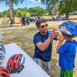 Attorney Reza Breakstone fits a child's helmet at the Dedham Bike Rodeo.