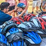 Attorney Reza Breakstone fits a young child for a new helmet at the Dedham Bike Rodeo on July 27, 2022.